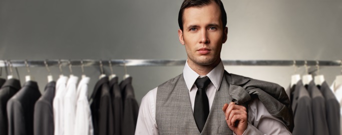 Businessman in classic vest against row of suits in shop